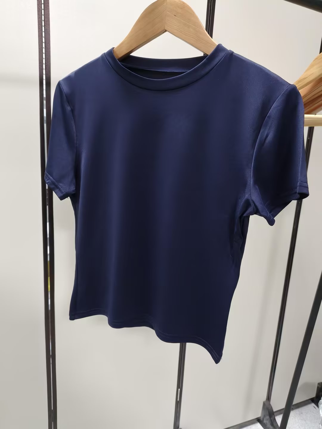 Navy short-sleeve cropped tee hanging from a plain wooden hanger